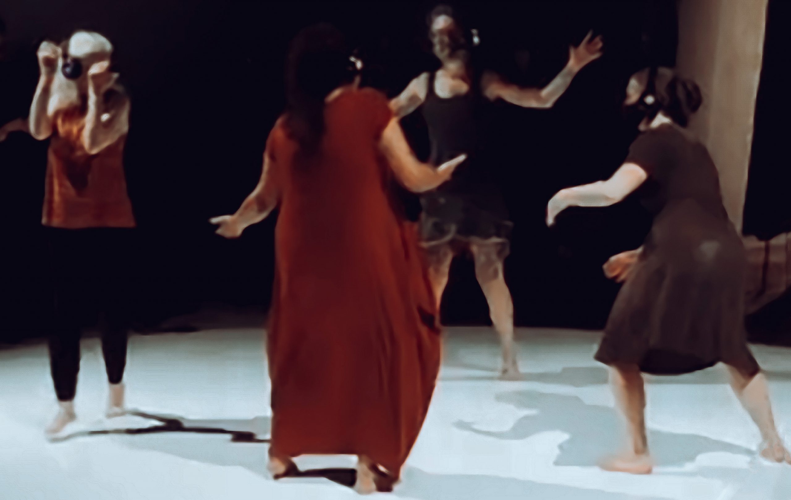 We see four dancers moving on a circular white dance floor, with their shadows dancing alongside